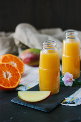 Mango and orange smoothie in transparent bottle.