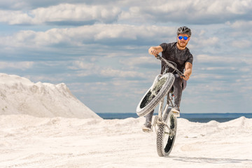 Training a bicyclist in a chalky quarry. A brutal man on a fat bike.	