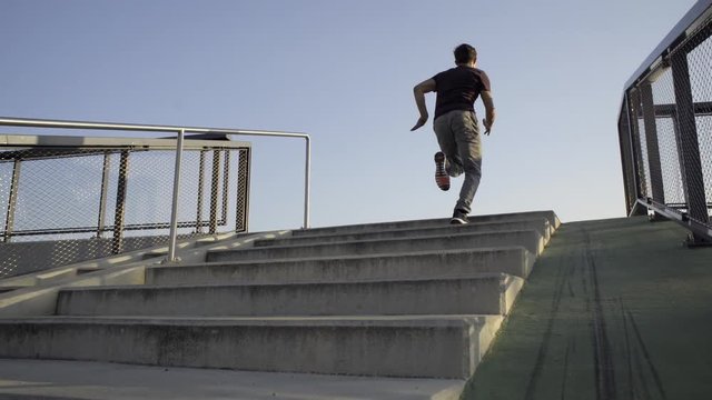 Freerunner running up a flight of stairs fast in sunset.