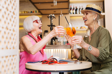 Beautiful day. Positive happy women drinking cocktail while being in the cafe