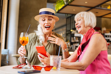 So funny. Happy positive women laughing while looking at the photo