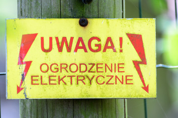 Fototapeta Warning sign with a live fence in polish language (uwaga ogrodzenie elektryczne pod napieciem). obraz
