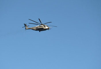 A marine helicopter in flight frozen against a blue background.