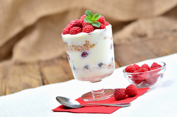 White bio yogurt with oatmeal and fresh raspberries in a glass - vertical photo