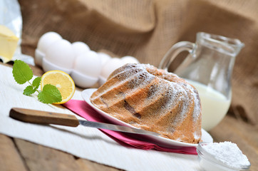 Homemade bundt cake sprinkled with sugar, lemon, melissa, milk, eggs and butter