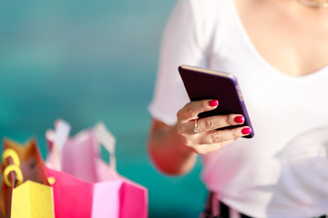 Cheerful girl with a phone and shopping bags at the mall. Quickly and easily make an order online, pay, get a profitable offer