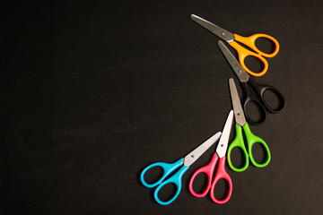 Many multicolored scissors on black table