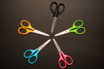 Many multicolored scissors on black table