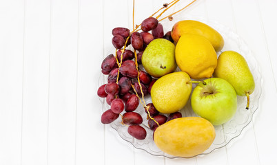 Still life Fruits, apple, pear, mango, lemon and fresh dates on glass plate. Concept Autumn harvest.