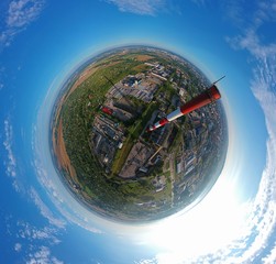 High brick chimney in city with green area, aerial little planet view