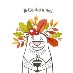 a cute bear with a wreath of autumn leaves and berries on his head with the inscription hello autumn and the cup of coffee latte