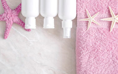 Soft modern bathroom decor for advertising, covers. Pink towels, cosmetic bottles, starfish on a light marble background table. Flat lay, top view, copy space 