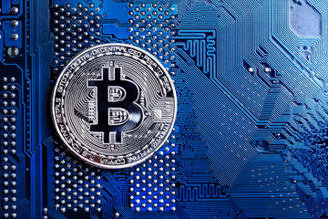 Silver bitcoin digital currency on blue circuit board. Bitcoin cryptocurrency security and mining...