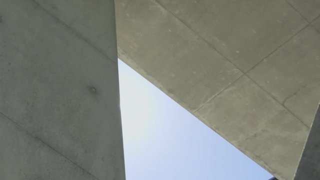 extreme low shot of a freerunner on a concrete wall doing a wallflip against the sun 