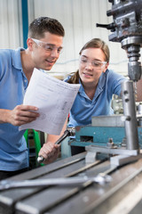 Engineer Instructing Female Apprentice On Use Of Drill