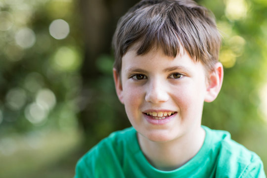 Portrait Of Happy Young Boy Sitting Outdoors