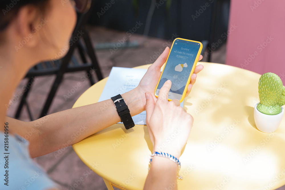 Wall mural checking forecast. modern remote worker checking weather forecast on her phone while planning picnic