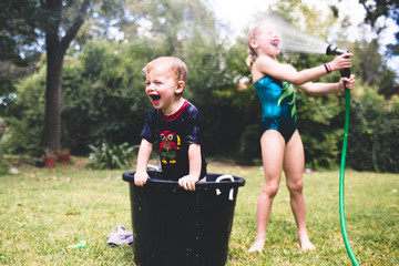Children playing and spraying hose in face