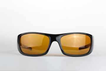 Sunglasses with black plastic frame and yellow glass on a white background