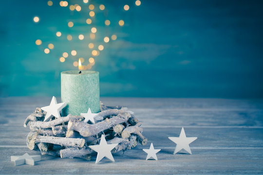 Christmas background with burning candle and bokeh lights