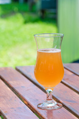 A glass of cold beer on wooden table in the garden