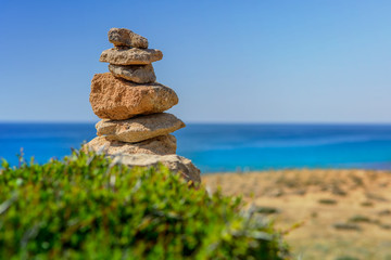 Wieża ułożona z kamieni, na plaży na tle morza