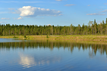 Summer landscape. Forest lake with reflection of cloud in Finnish Lapland