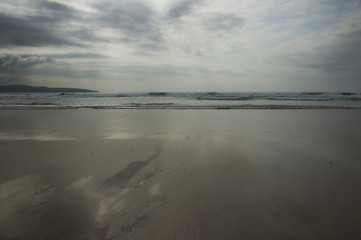 sandy beach and reflections under a grey sky 