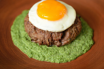 steak with egg on top of a clay plate