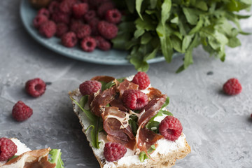 Sandwiches with whole grain bread, homemade cheese, arugula, ham and juicy raspberry. Healthy snack.