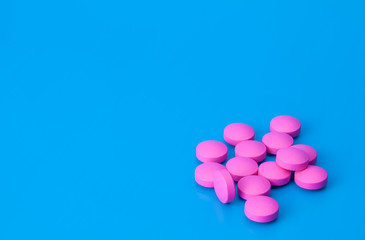 Bright pink pills on a blue background.