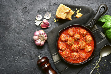 Fototapeta na wymiar Spicy meatballs in tomato sauce in a cast iron pan.Top view with copy space.