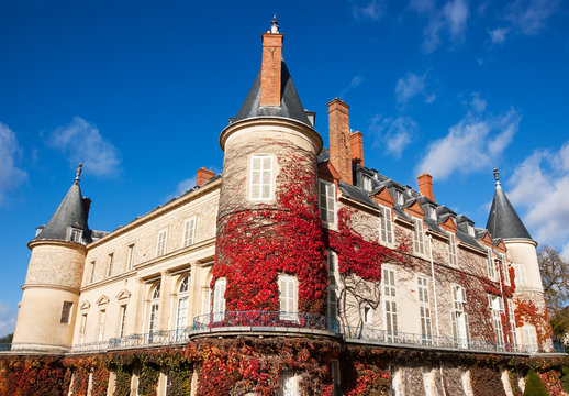 Chateau de Rambouillet overgrown with red grape leaves in autumn. Autumn in France.