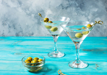 Martini cocktail with green olives on blue wood background