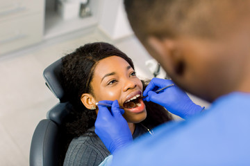 High angle view of female african american patient being examined by dentist in clinic