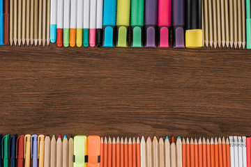 Obraz premium elevated view of arranged colorful pencils and markers on wooden table