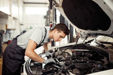Fototapeta na wymiar Safety sirst: a good-looking car mechanic is checking the engine