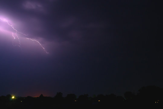 bright flash of lightning illuminated the night sky and dyed clouds in a blue violet color