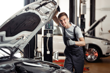 An attractive young car mechanic is smiling: car service and mai