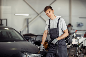 An attractive young mechanic in professinal unifors is at work at a car service