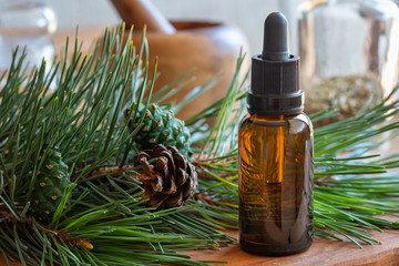 A bottle of pine essential oil with fresh pine branches