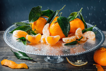 Ripe tangerines with leaves on a silver tray