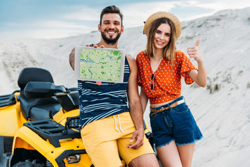 beautiful young couple with atv showing digital tablet with navigation website on screen and thumb up at desert © LIGHTFIELD STUDIOS