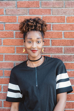A young african american woman posing in front of a brick wall