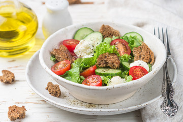 Appetizer of tomatoes, cucumbers, lettuce, mozzarella and bread. Tuscan panzanella salad with olive oil, salt and pepper dressing