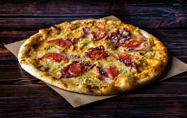 Pizza with hum, sesame and tomato on a wooden table