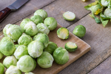 Raw brussels sprouts on wooden cutting desk.