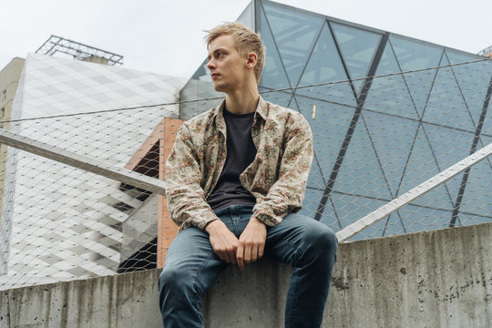 Young man with floral pattern shirt on a cityscape.