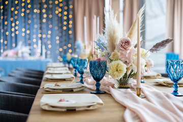 Beautiful and exquisite decoration of the wedding celebration. Banquet served table with a beige pink tablecloth, plates and candlesticks with candles.
