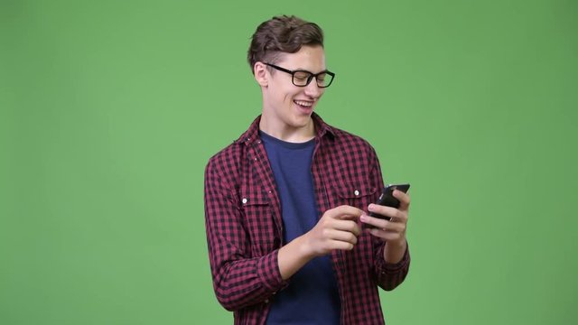 Young handsome teenage nerd boy using phone